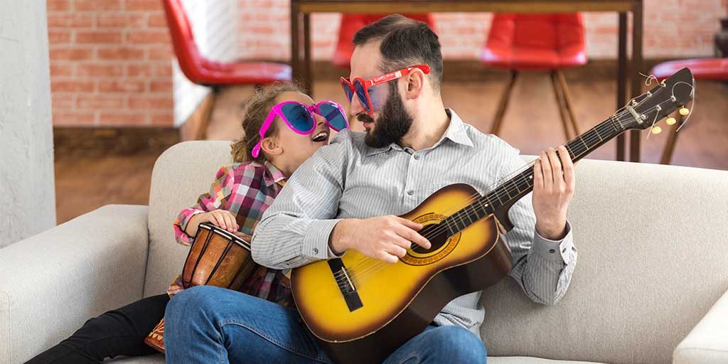 Dad and daughter wearing funny glasses while playing instruments.