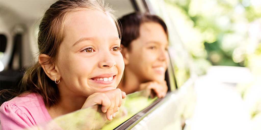 Little girl smiling as she looks out the window.