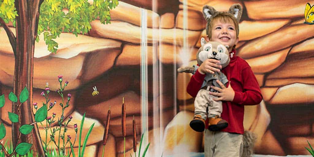 Kid smiling as he holds a plush doll