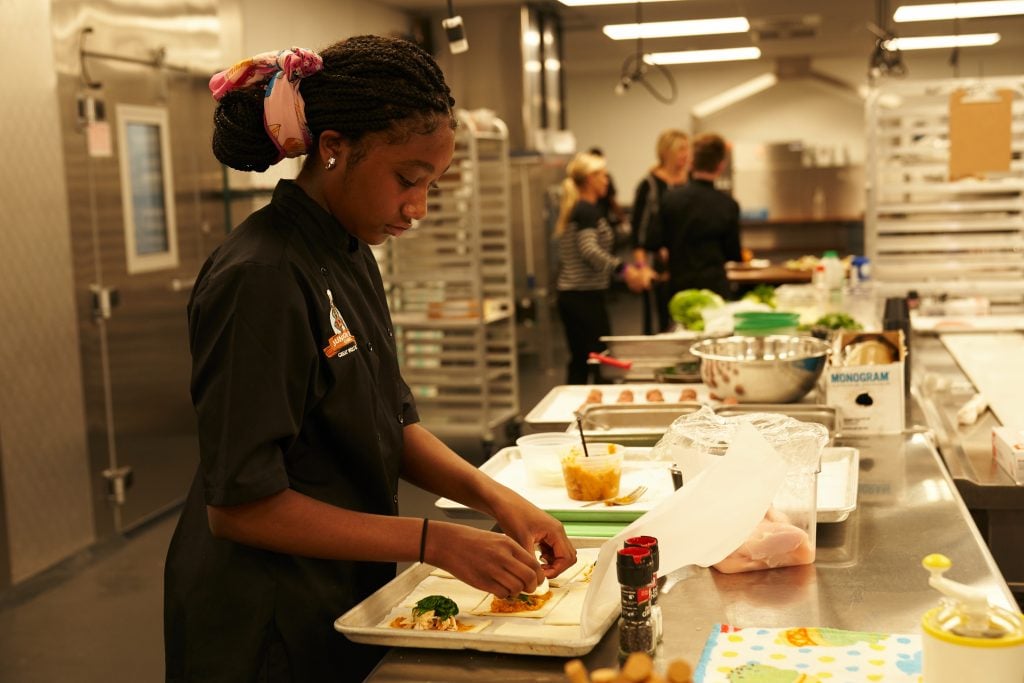 Girl preparing new menu item in a kitchen at a Great Wolf Resort.