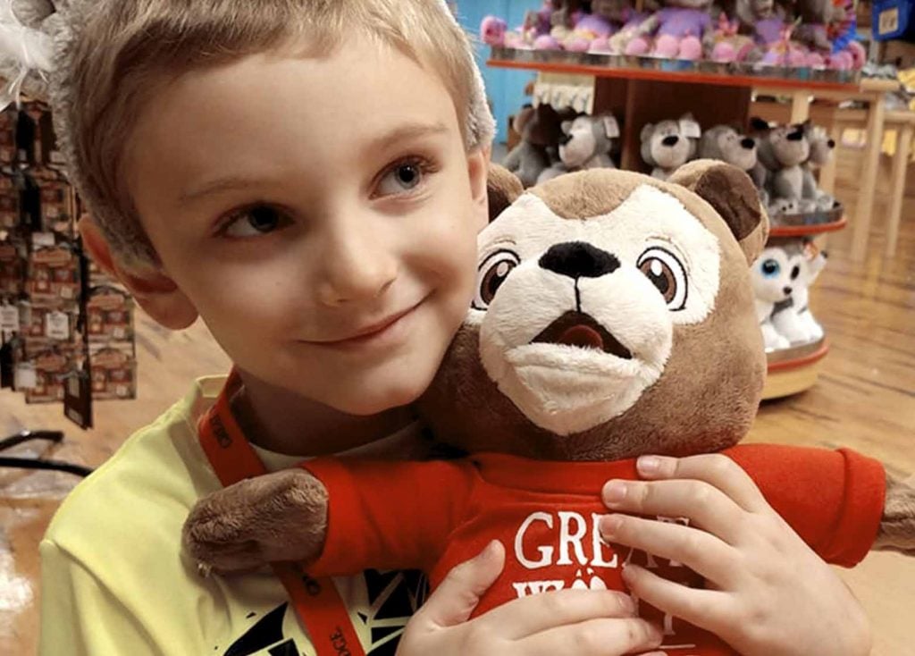 young boy holding stuffed animal wolf toy in Great Wolf Lodge gift shop