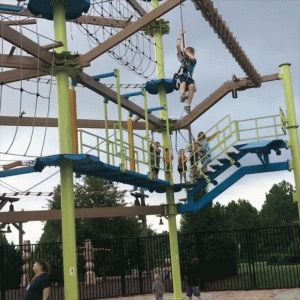 young boy flying through the air in a harness on the Great Wolf Lodge ropes course