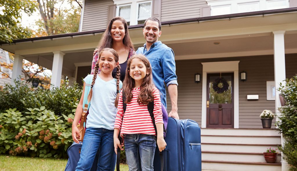 photo of a family in front of house with bags packed