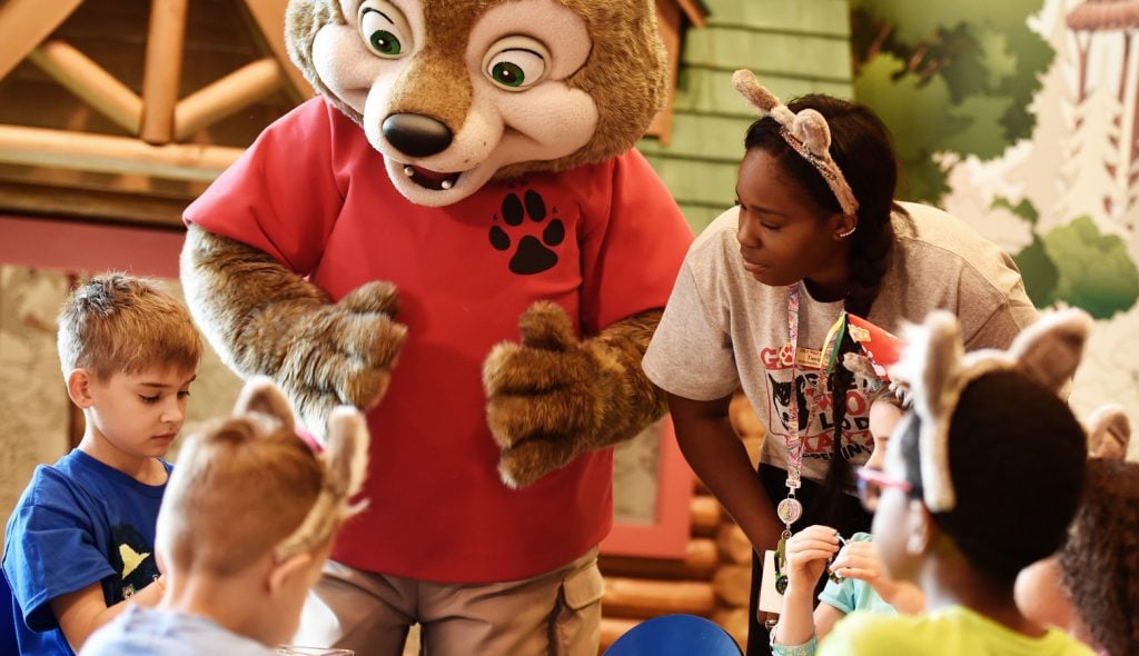 Kids gathered around a Great Wolf kids character and staff member.