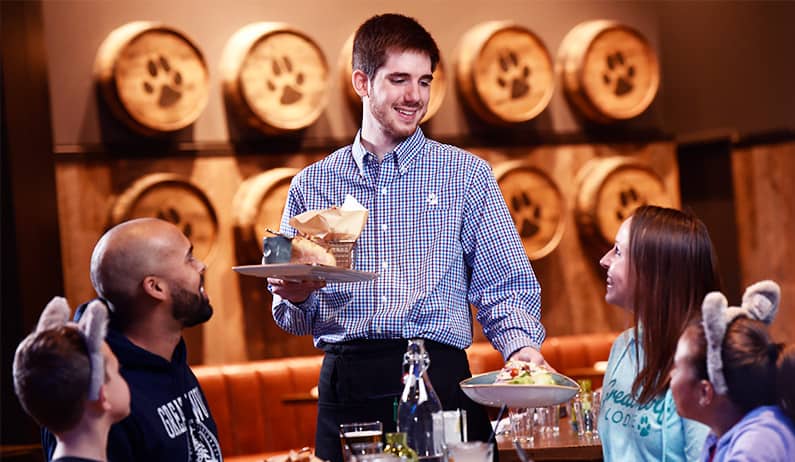 Server at Great Wolf Lodge's barn wood serving a family of four