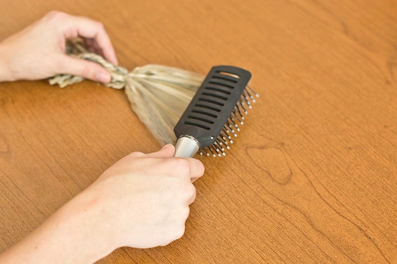 Hands brushing DIY wolf tail for Halloween costume