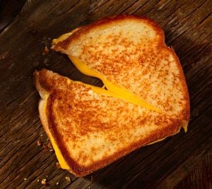 A grilled cheese sandwich cut in half and halfway peeled on a table top.