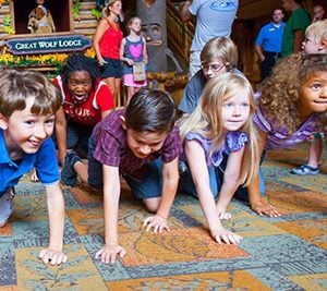 Children on hands and knees doing a wolf walk at a Great Wolf Lodge.