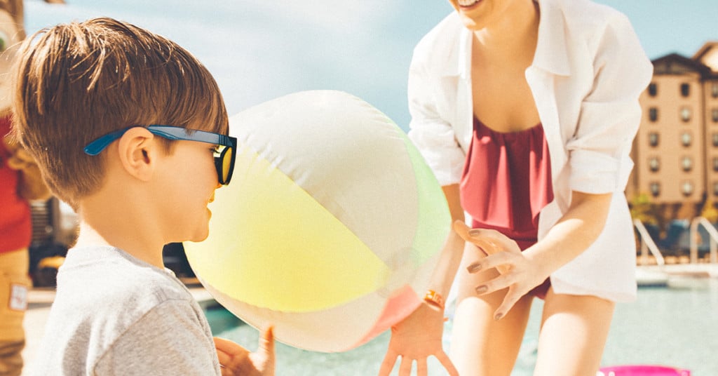 Young boy and his mom play with a beach ball.