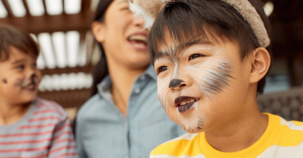 Close up of a boy with raccoon face paint.