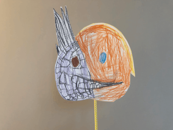 DIY paper puppet character with two faces on a stick.