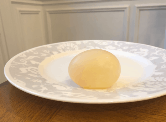 Peeled translucent-looking egg sitting on a plate.