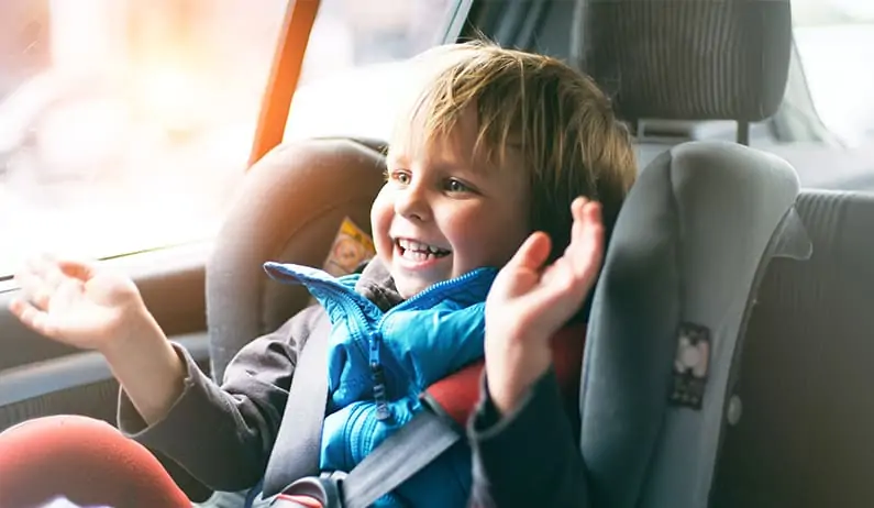 Little boy smiling in car seat