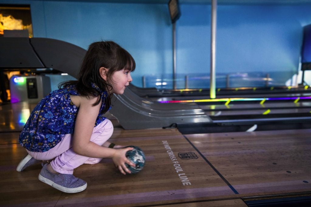 Little girl bowling at Ten Paw Alley at Great Wolf Lodge.