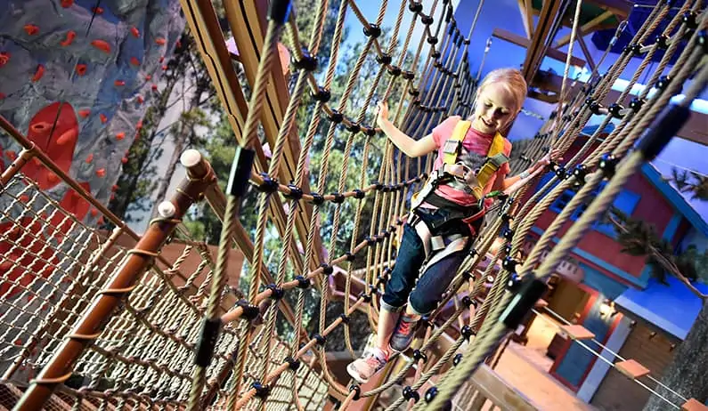 Girl climbing through ropes course at Great Wolf Lodge adventure park