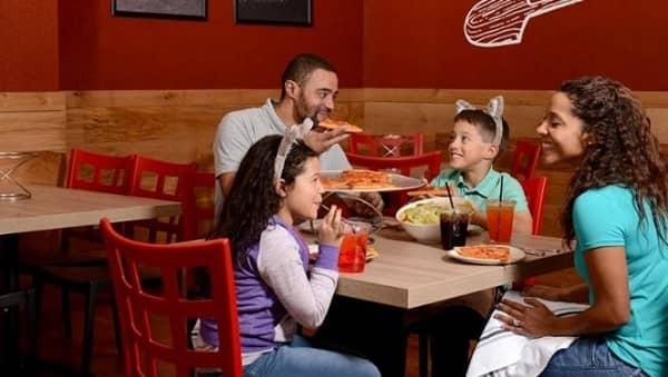 family eating pizza at restaurant table