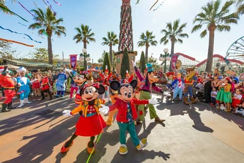 Minnie and Mickey Mouse surrounded by palm trees during a character parade at Disneyland in Southern California