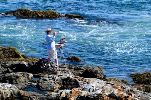 A man taking photos of the ocean at Acadia National Park
