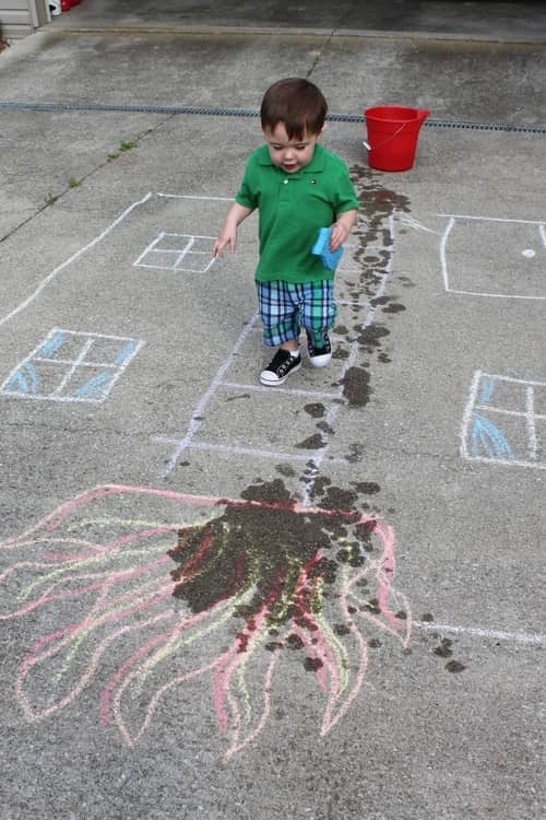 Little boy playing on the sidewalk with chalk