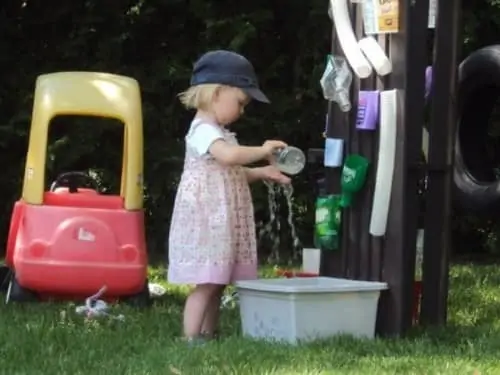 Little girl playing with home-made water wall