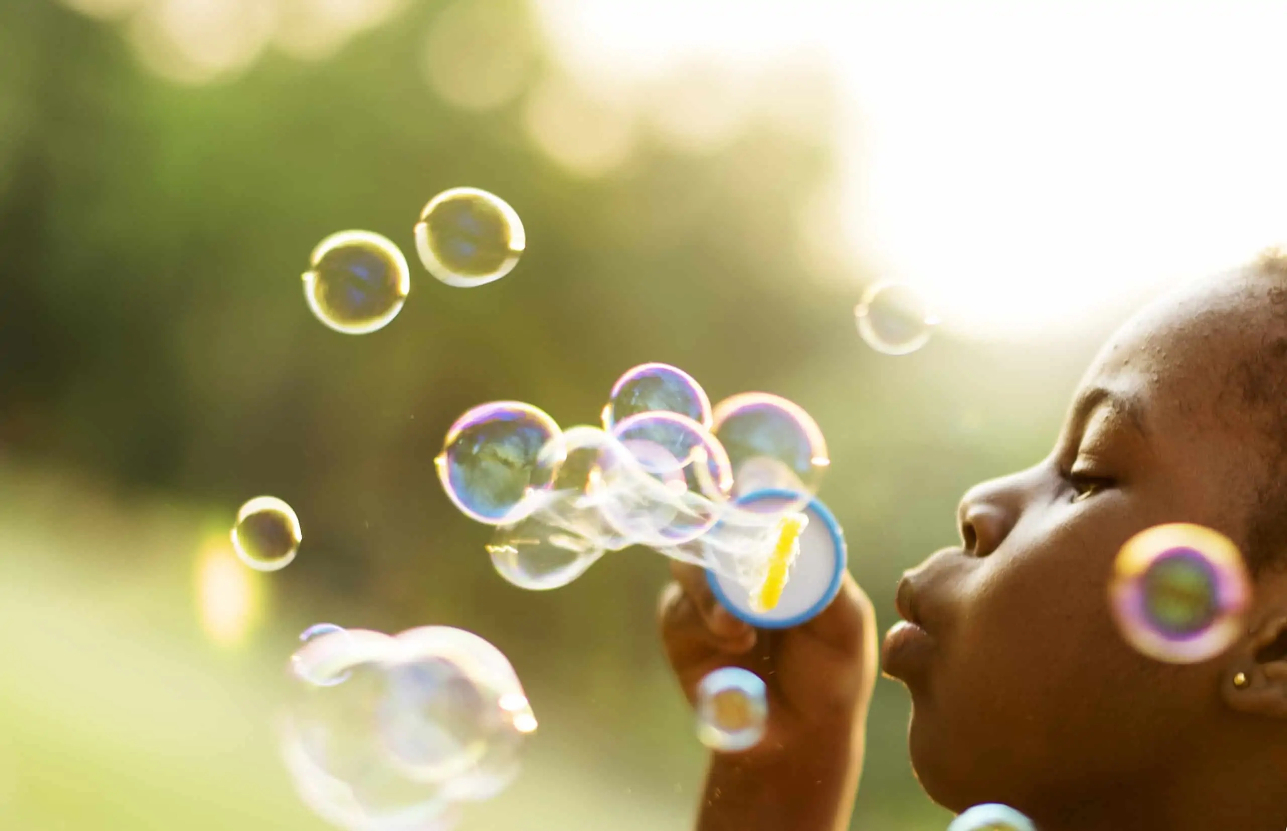 little girl blowing bubbles outside