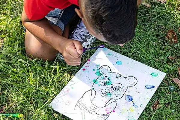 little boy creating bubbles art with different colors of paint