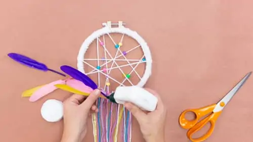 gluing colored feathers to DIY dreamcatcher