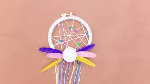 white felt rose, colored yarn, feathers attached to DIY dreamcatcher