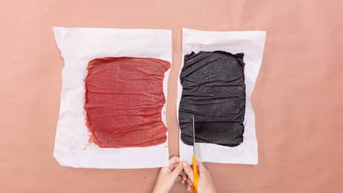 cutting white parchment paper with baked fruit spread in half