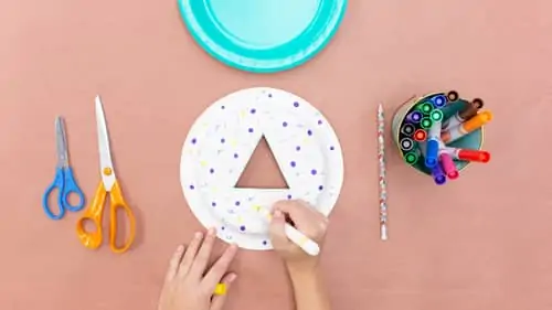 two scissors, paper plate with purple and yellow polka dots and triangle cut out and colored markers