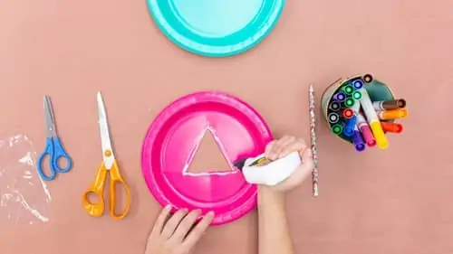 two scissors, pink paper plate with triangle cut out, pencil and colored markers