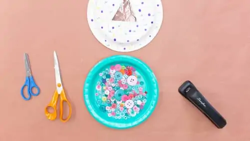 two scissors, stapler, paper plate with polka dots and paper plate full of buttons