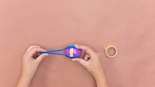 tape blue plastic spoons to either side of purple plastic egg