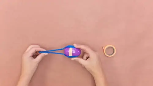 tape blue plastic spoons to either side of purple plastic egg