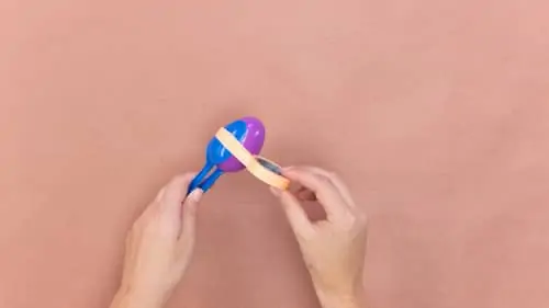 wrape blue plastic spoons to purple plastic egg using orange decorative tape