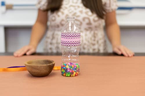 plastic water bottle with purple decorative tape and colored beads