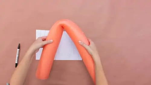 orange pool noodle folded in half, white felt and black pen