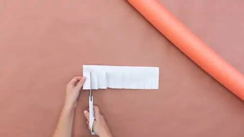 woman cutting white felt and orange pool noodle