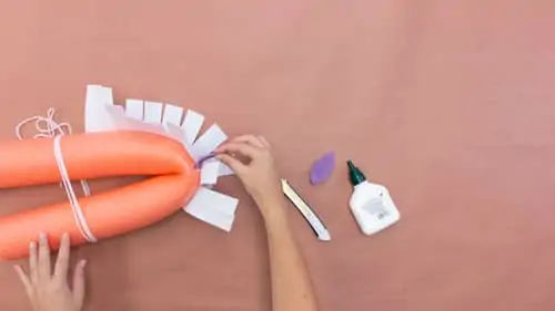 white felt sticking out of tied orange pool noodle and a bottle of glue