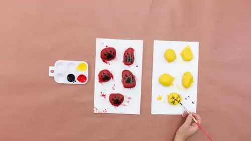 create black paint to draw arrow onto yellow painted rocks