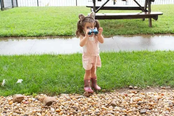 little girl playing in the yard with binoculars