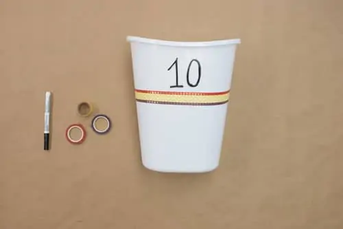 white bucket with number ten and three rows of decorative tape. rolls and black pen next to bucket