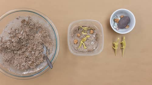 bowls of mixture, pebbles and dinosaur figurines 