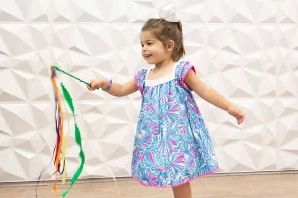 little girl playing with homemade ribbon wand