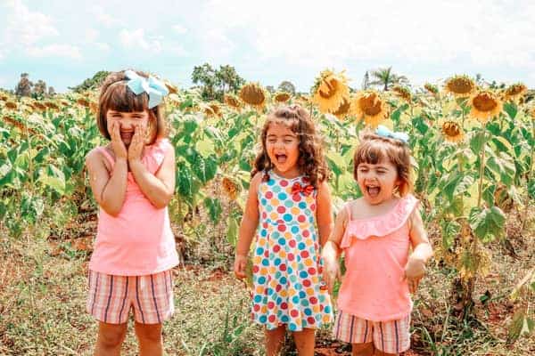 three little girls in front of sun flowers