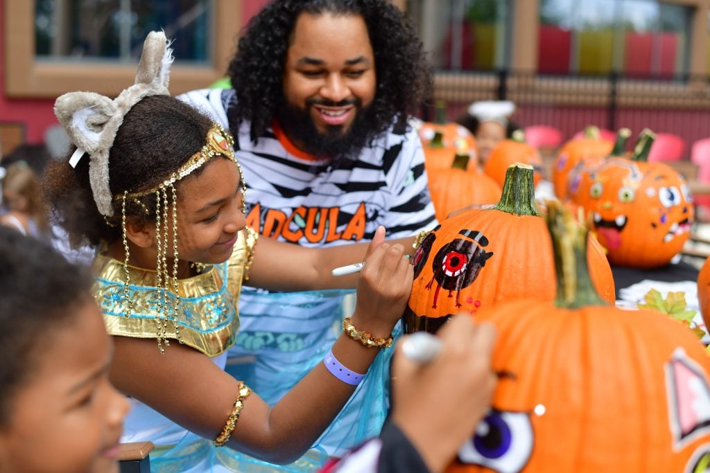 kid decorating pumpkin with markers