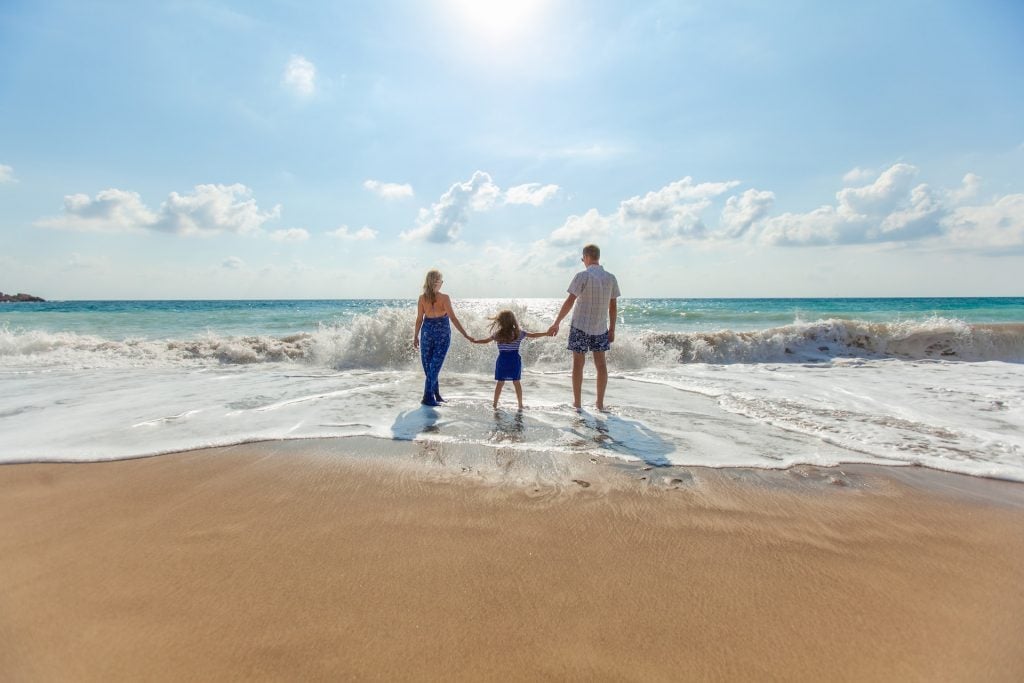 parents holding kids hand in the ocean