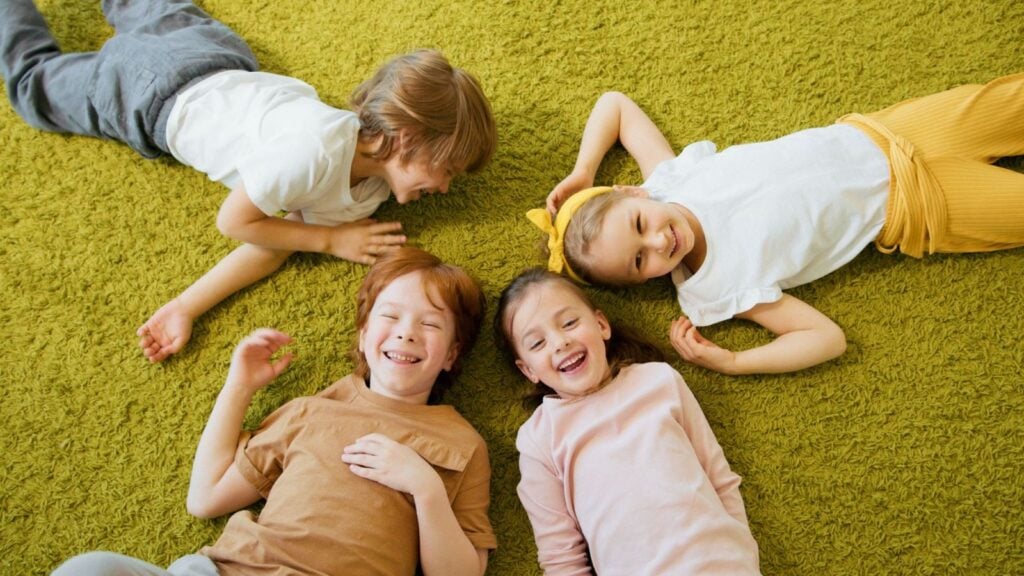 kids laying outside on grass in summer doing August trivia