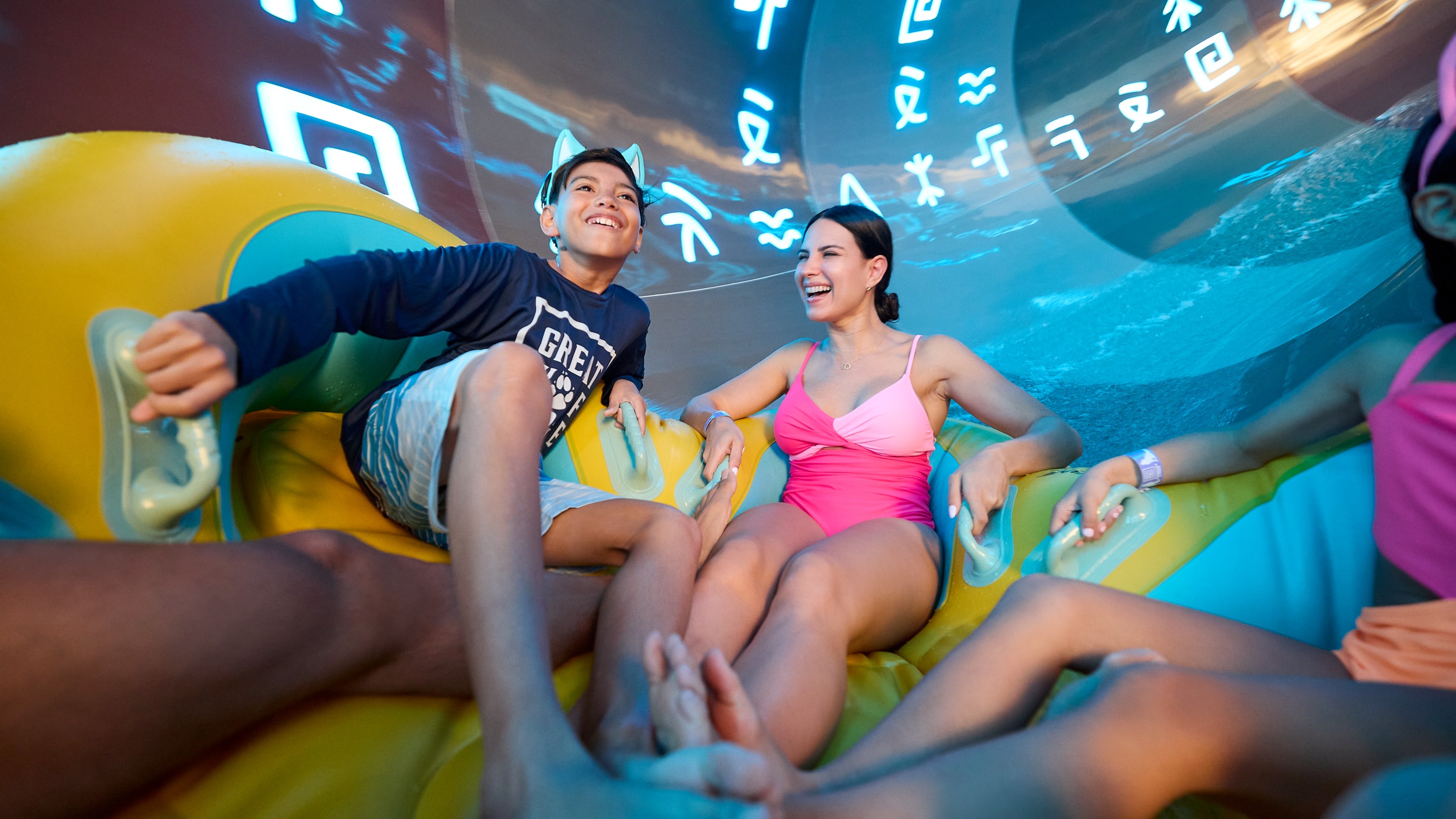 mother and son laughing as they slide down a water pipe on a tube