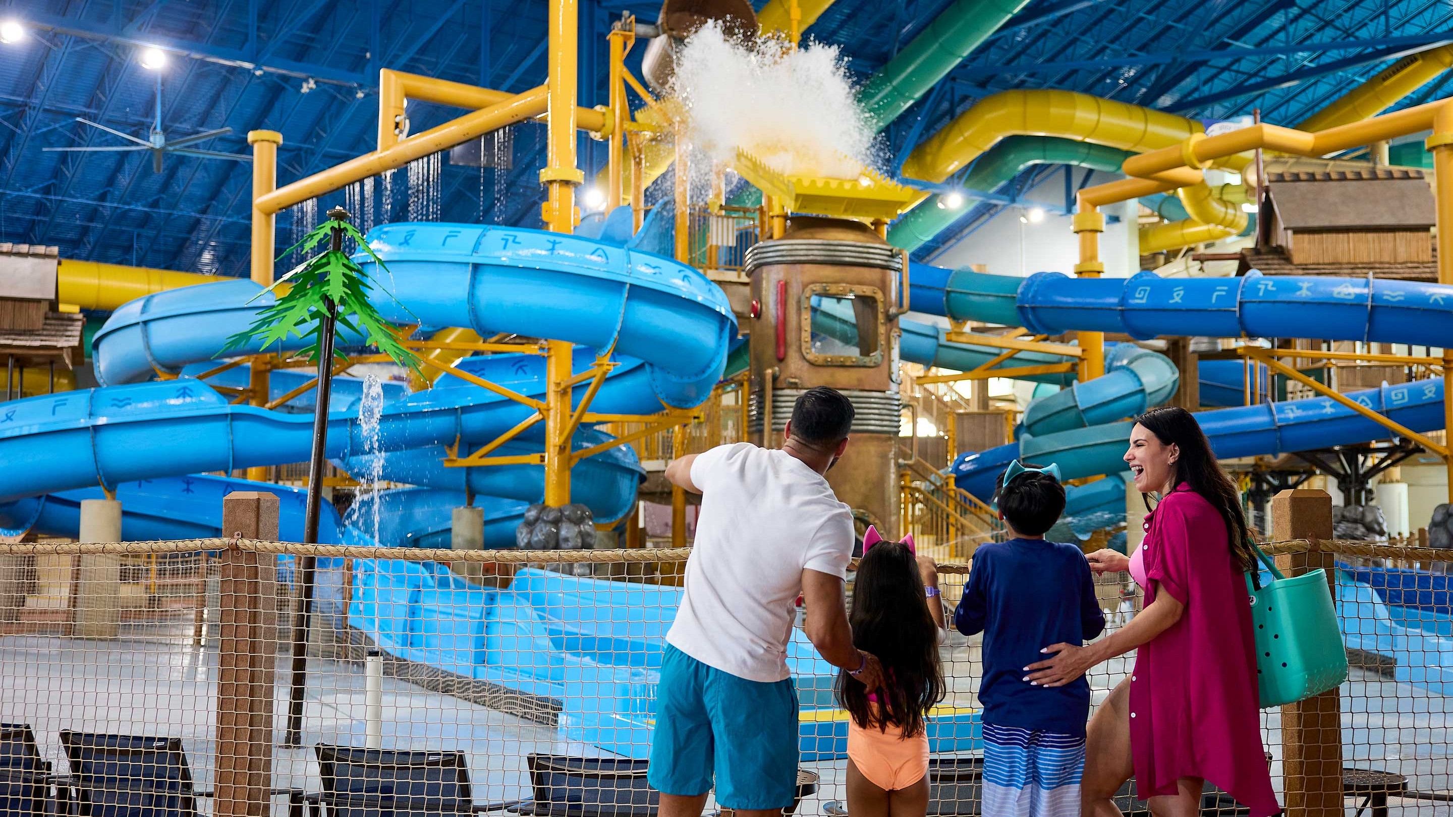 family watching water fall from a large bucket inside a water park